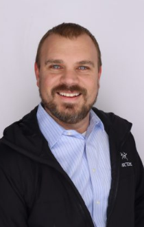 Image: Headshot of Dan Rife, wearing blue and white striped shirt, black jacket, with short brown hair.
