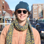 Andrew Van Baal, white man wearing sunglasses, yellow and blue knitted scarf, and pink button up shirt.