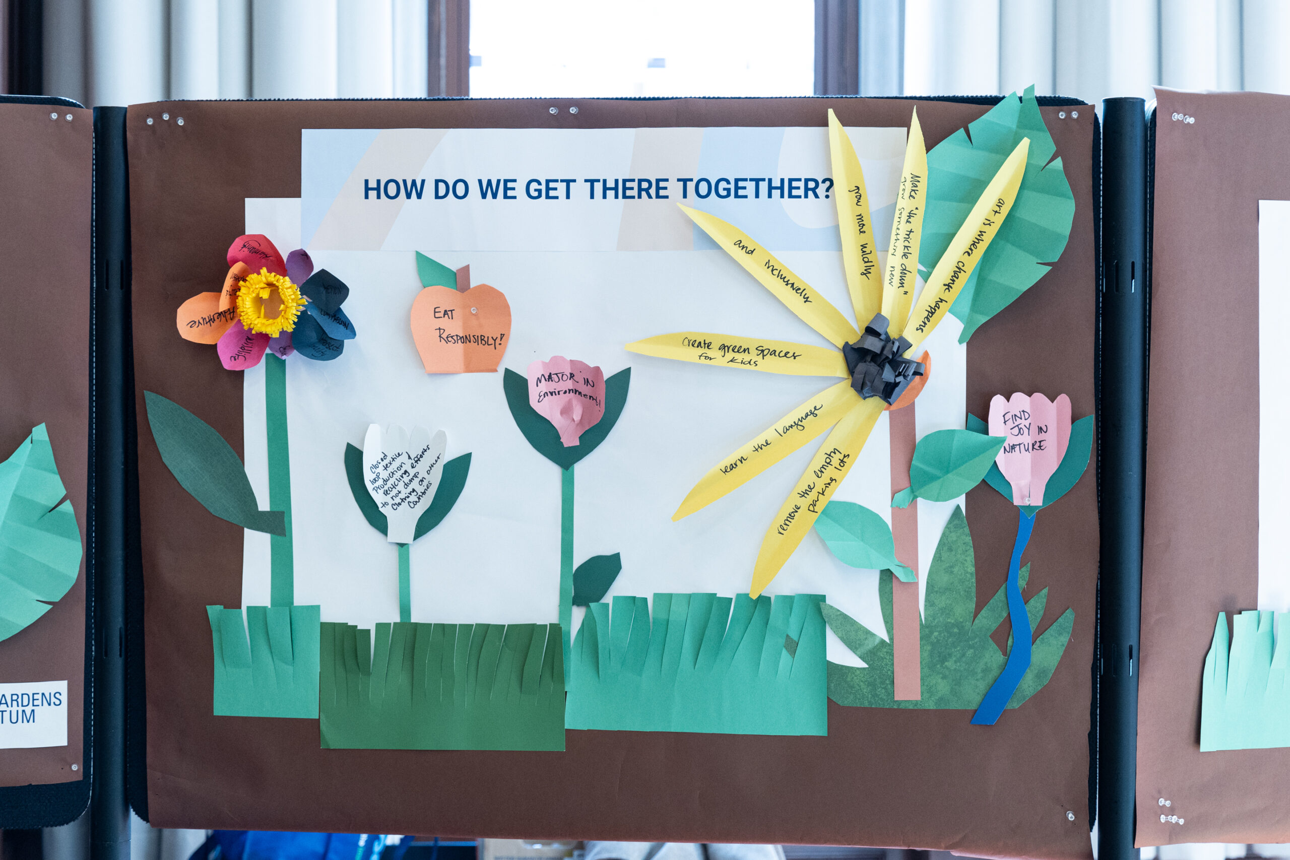 Poster with the title "How Do We Get There Together?" with hand written responses that form a colorful flower garden.